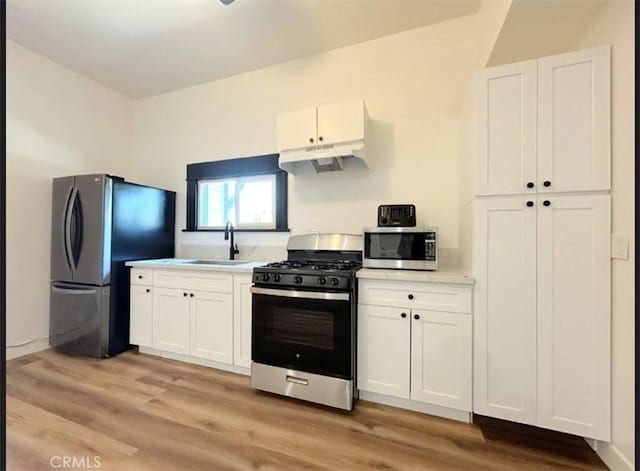 724 W 2nd St, Pomona, CA 91766 - kitchen with stainless steel appliances, under cabinet range hood, light countertops, and white cabinetry