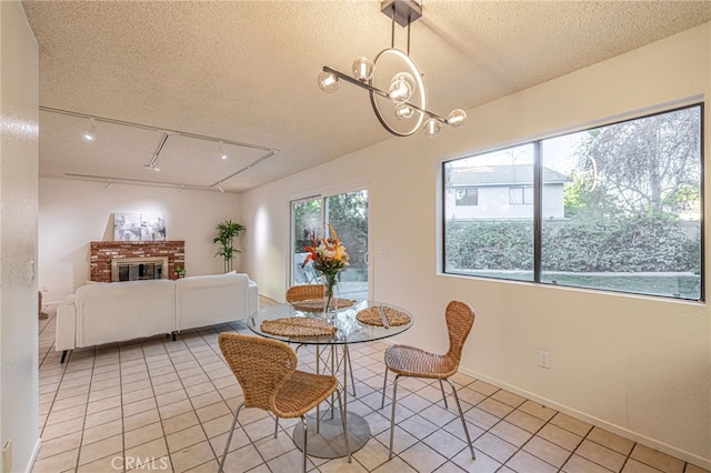 44118 Ruthron Ave, Lancaster, CA 93536 - dining room with a textured ceiling, light tile patterned flooring, a brick fireplace, a chandelier, and rail lighting