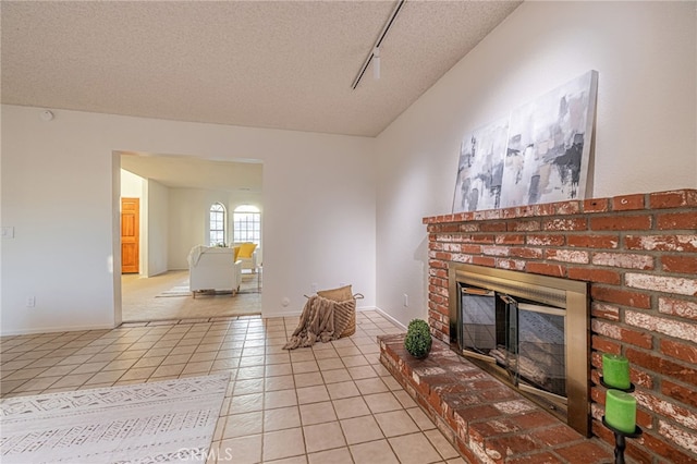 44118 Ruthron Ave, Lancaster, CA 93536 - living room featuring light tile patterned floors, a fireplace, a textured ceiling, and track lighting