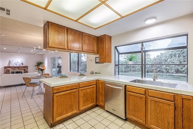 44118 Ruthron Ave, Lancaster, CA 93536 - kitchen with stainless steel dishwasher, brown cabinetry, open floor plan, and light tile patterned floors