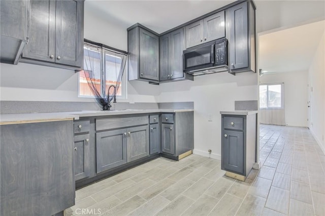 1964 E 114th St, Los Angeles, CA 90059 - kitchen featuring black microwave, light countertops, gray cabinets, and light wood finished floors
