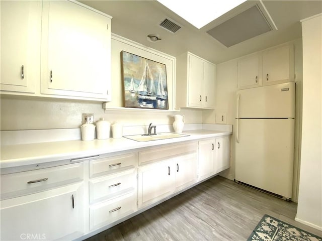 1441 Monterey Rd Unit M2-61J, Seal Beach, CA 90740 - kitchen featuring freestanding refrigerator, white cabinets, light countertops, and light wood-type flooring