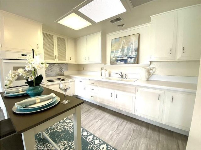 1441 Monterey Rd Unit M2-61J, Seal Beach, CA 90740 - kitchen featuring white oven, white cabinets, light wood-style flooring, and light countertops