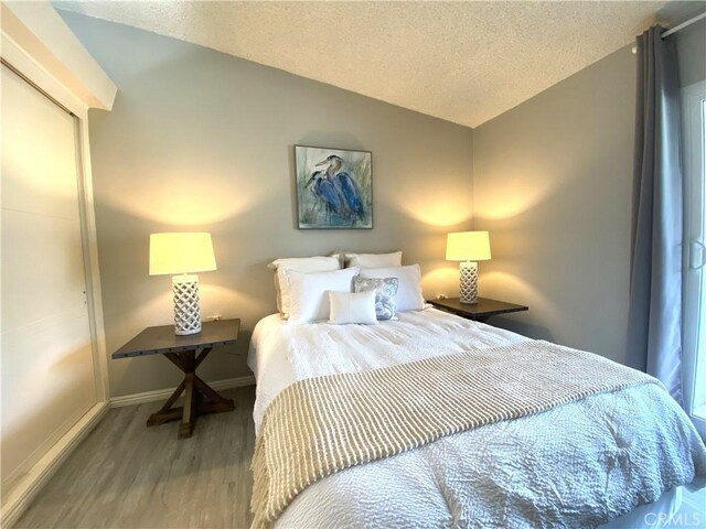 1441 Monterey Rd Unit M2-61J, Seal Beach, CA 90740 - bedroom with vaulted ceiling, a textured ceiling, and wood finished floors