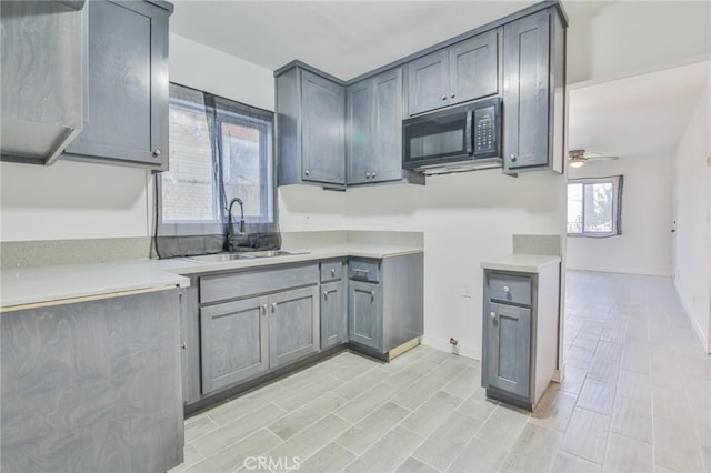 1962 E 114th St, Los Angeles, CA 90059 - kitchen with black microwave, a ceiling fan, light countertops, and gray cabinetry