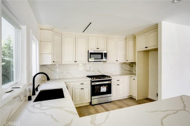 1038 N Columbus Ave, Glendale, CA 91202 - kitchen with stainless steel appliances, open shelves, tasteful backsplash, light stone counters, and light wood-style floors