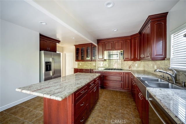 1038 N Columbus Ave, Glendale, CA 91202 - kitchen with stainless steel appliances, reddish brown cabinets, decorative backsplash, a kitchen island, and light stone countertops