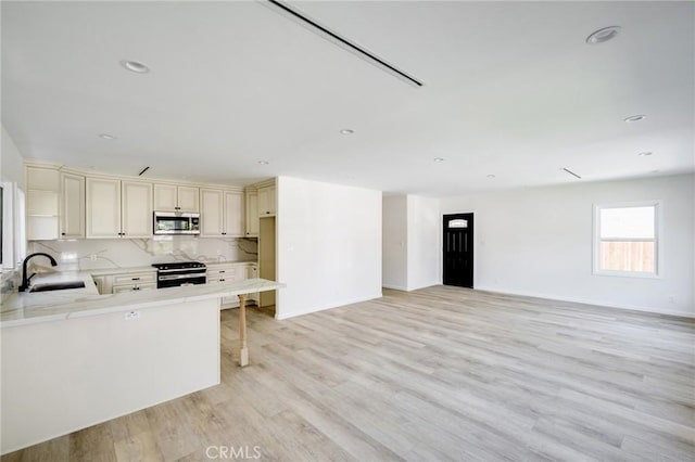 1038 N Columbus Ave, Glendale, CA 91202 - kitchen featuring stainless steel microwave, gas range, cream cabinets, light countertops, and light wood-type flooring