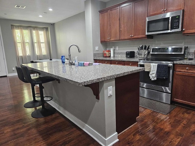 7508 Eagle Dr, Santee, CA 92071 - kitchen with stainless steel appliances, dark wood finished floors, an island with sink, a kitchen bar, and recessed lighting