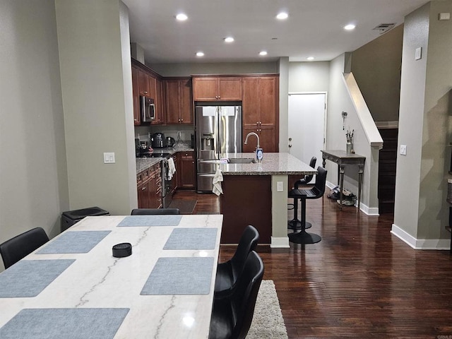7508 Eagle Dr, Santee, CA 92071 - kitchen with appliances with stainless steel finishes, an island with sink, a kitchen breakfast bar, dark wood-style flooring, and recessed lighting