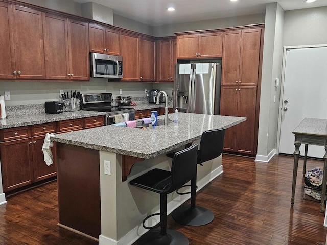 7508 Eagle Dr, Santee, CA 92071 - kitchen with appliances with stainless steel finishes, dark wood finished floors, recessed lighting, a breakfast bar area, and a center island with sink