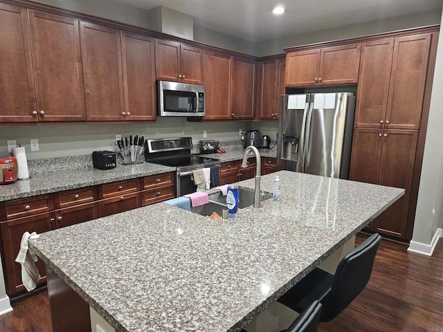7508 Eagle Dr, Santee, CA 92071 - kitchen with appliances with stainless steel finishes, dark wood-style flooring, a kitchen bar, light stone counters, and a center island with sink