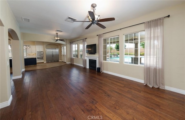 125 W Franklin Ave, Ridgecrest, CA 93555 - unfurnished living room with a ceiling fan, arched walkways, dark wood-type flooring, and a fireplace