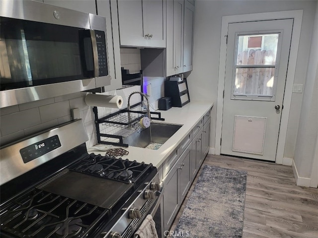 942 Front St, Perris, CA 92570 - kitchen with appliances with stainless steel finishes, gray cabinets, wood finished floors, backsplash, and light countertops