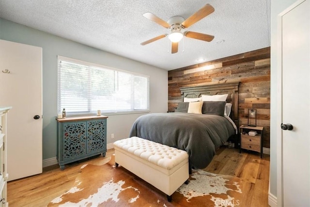 7635 Sombrilla Ave, Atascadero, CA 93422 - bedroom featuring wooden walls, wood finished floors, a textured ceiling, a ceiling fan, and an accent wall