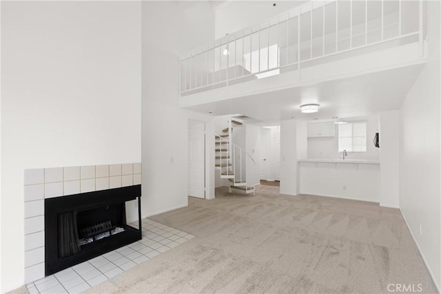 20331 Bluffside Unit A408, Huntington Beach, CA 92646 - unfurnished living room featuring stairs, light carpet, a fireplace, and a towering ceiling
