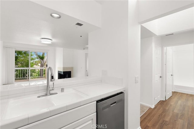 20331 Bluffside Unit A408, Huntington Beach, CA 92646 - kitchen featuring dishwasher, wood finished floors, tile counters, and white cabinets