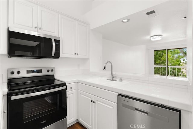20331 Bluffside Unit A408, Huntington Beach, CA 92646 - kitchen featuring stainless steel appliances, white cabinets, and tile countertops