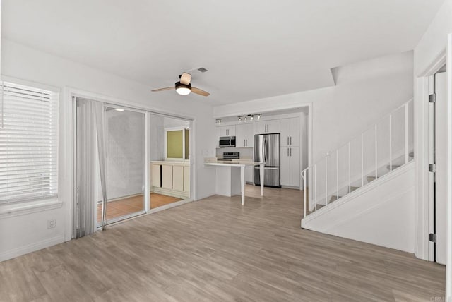 155 Countrywood Ln, Encinitas, CA 92024 - unfurnished living room with ceiling fan, stairs, and light wood-type flooring