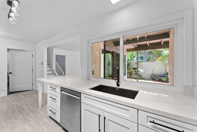 155 Countrywood Ln, Encinitas, CA 92024 - kitchen featuring stainless steel dishwasher, white cabinetry, light stone countertops, and light wood-style floors
