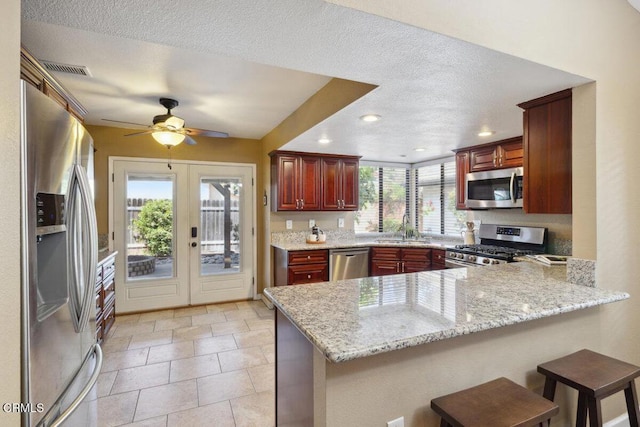 116 La Veta Dr, Camarillo, CA 93012 - kitchen with stainless steel appliances, a peninsula, reddish brown cabinets, ceiling fan, and recessed lighting