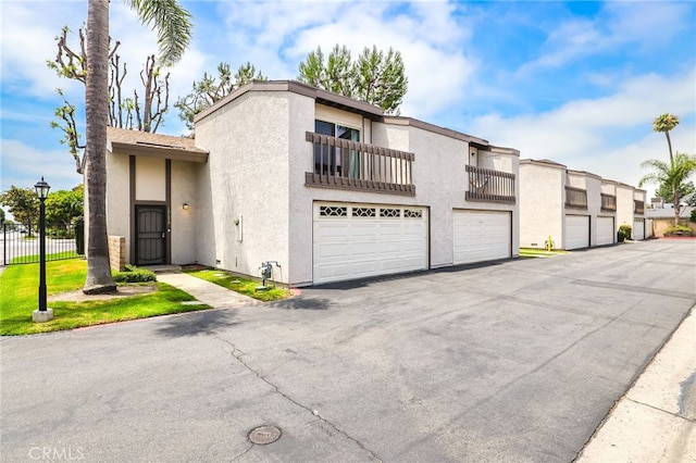 12698 Shearer Ln, Garden Grove, CA 92843 - multi unit property with stucco siding, a garage, asphalt driveway, and a balcony