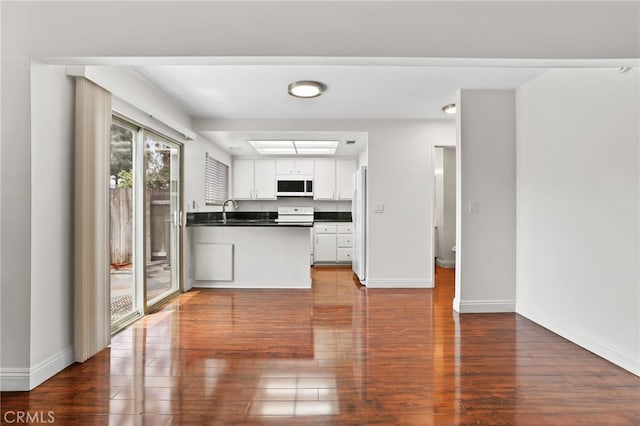 12698 Shearer Ln, Garden Grove, CA 92843 - kitchen with white appliances, dark countertops, dark wood finished floors, white cabinetry, and a peninsula