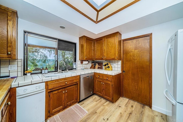 2278 Casitas Del Sol, Fallbrook, CA 92028 - kitchen featuring freestanding refrigerator, stainless steel dishwasher, light wood-style flooring, tasteful backsplash, and brown cabinets