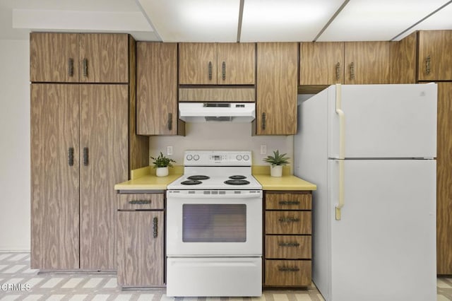 13208 Village 13 Unit 13, Camarillo, CA 93012 - kitchen featuring white appliances, under cabinet range hood, light countertops, and brown cabinetry