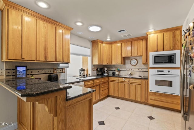 30100 Sunland Way, Tehachapi, CA 93561 - kitchen with white appliances, tasteful backsplash, a peninsula, dark stone countertops, and light tile patterned floors