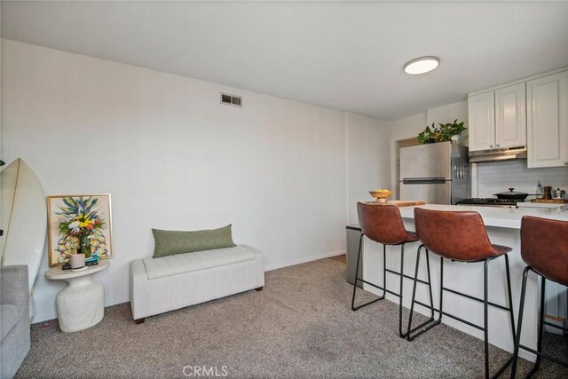 1413 Avenida De La Estrella, San Clemente, CA 92672 - kitchen with freestanding refrigerator, under cabinet range hood, a breakfast bar, light carpet, and light countertops