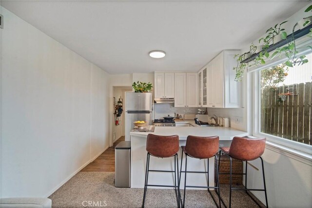 1413 Avenida De La Estrella, San Clemente, CA 92672 - kitchen featuring freestanding refrigerator, a peninsula, glass insert cabinets, a breakfast bar, and light countertops
