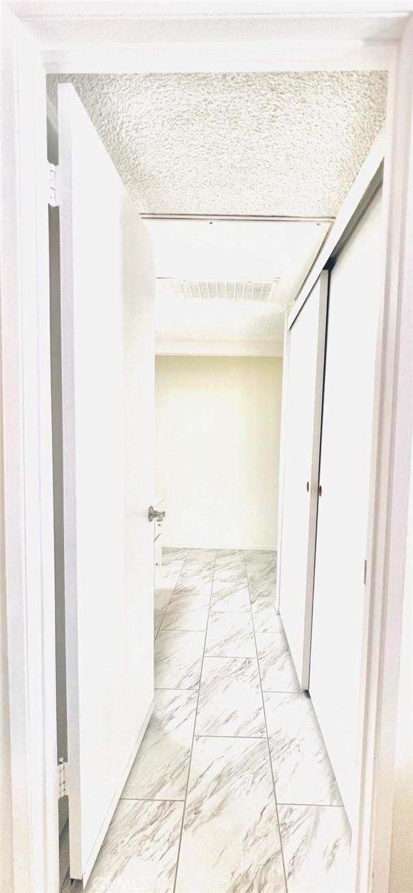 23515 Lyons Ave Unit 232, Valencia, CA 91355 - hallway featuring light marble finish floors