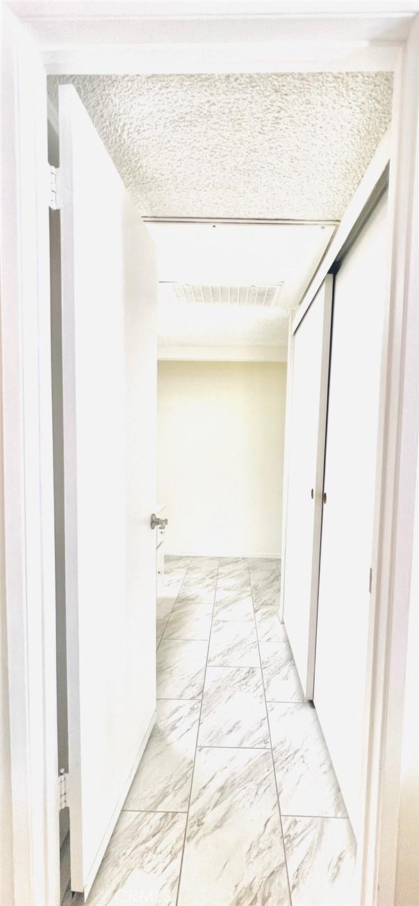 23515 Lyons Ave Unit 232, Valencia, CA 91355 - hallway with light marble finish floors