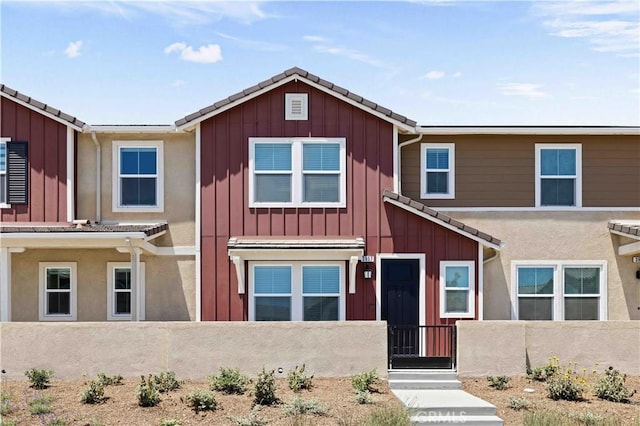 3957 E Huntington St, Ontario, CA 91761 - townhome / multi-family property with a fenced front yard, board and batten siding, a gate, and a tiled roof