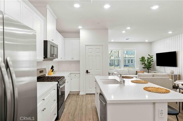 3957 E Huntington St, Ontario, CA 91761 - kitchen with appliances with stainless steel finishes, open floor plan, light wood-style floors, an island with sink, and white cabinetry