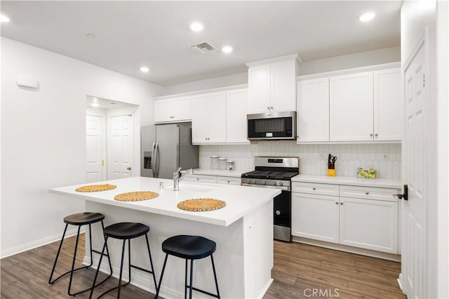 3957 E Huntington St, Ontario, CA 91761 - kitchen featuring appliances with stainless steel finishes, an island with sink, decorative backsplash, white cabinetry, and recessed lighting