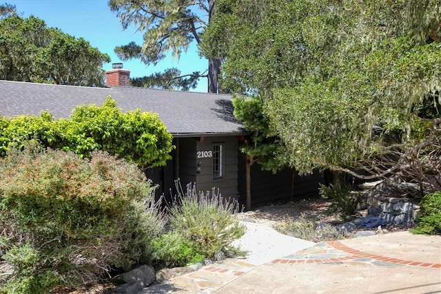 2103 Benson Ave, Cambria, CA 93428 - view of property hidden behind natural elements featuring a shingled roof and a chimney