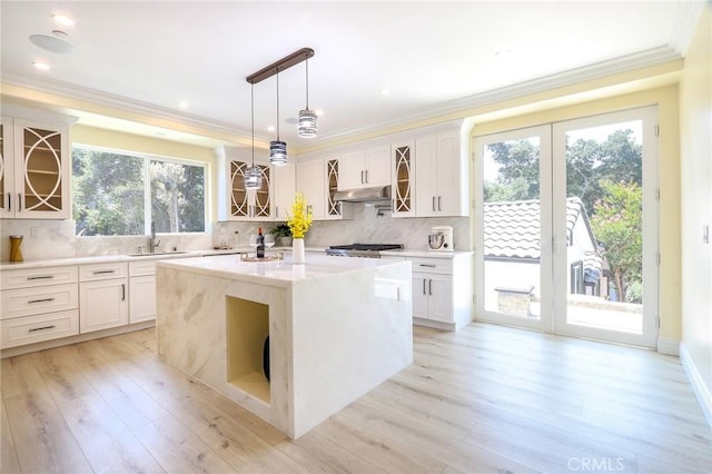 3264 E Holt Ave, West Covina, CA 91791 - kitchen featuring under cabinet range hood, glass insert cabinets, decorative backsplash, ornamental molding, and white cabinetry