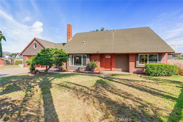 2041 Caballeros Rd, Norco, CA 92860 - view of front of house with brick siding, a chimney, a front yard, driveway, and roof with shingles