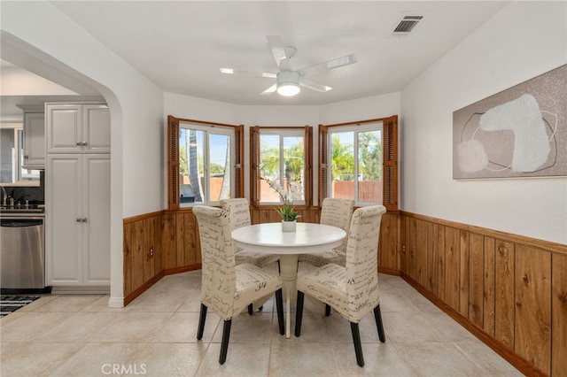 2041 Caballeros Rd, Norco, CA 92860 - dining room featuring a wainscoted wall, wood walls, healthy amount of natural light, a ceiling fan, and light tile patterned flooring