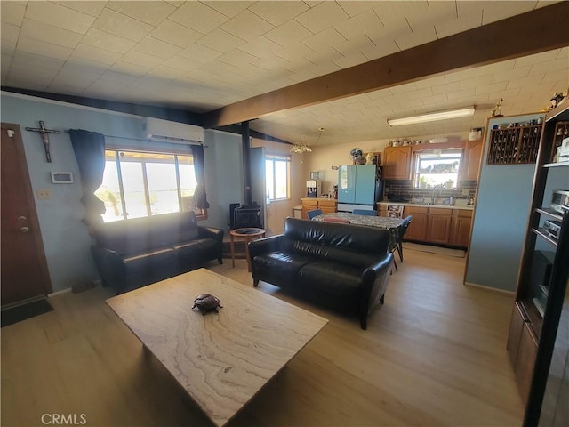 5566 Oleta Rd, Landers, CA 92285 - living room with a wall mounted AC, a wood stove, light wood finished floors, and beam ceiling