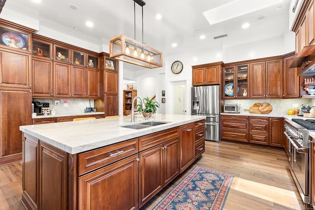 10166 Rancho Roble Rd, Escondido, CA 92026 - kitchen with appliances with stainless steel finishes, a skylight, a kitchen island with sink, backsplash, and wood finished floors