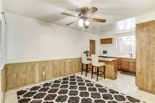 1593 W Carter St, Bloomington, CA 92316 - kitchen with brown cabinets, a kitchen breakfast bar, a textured ceiling, light countertops, and ceiling fan