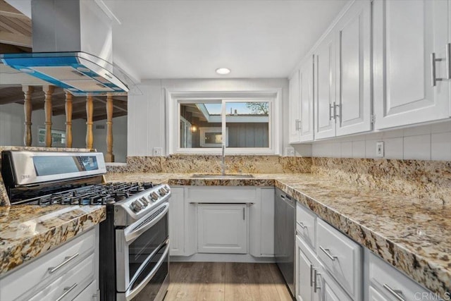 8123 Palm St, Lemon Grove, CA 91945 - kitchen featuring appliances with stainless steel finishes, island range hood, white cabinetry, light wood finished floors, and recessed lighting
