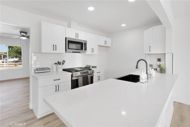 9546 San Pablo Ave, Hesperia, CA 92345 - kitchen featuring appliances with stainless steel finishes, light countertops, light wood-type flooring, white cabinets, and backsplash
