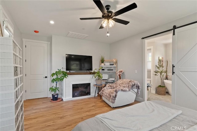 212 Valley View Dr, Paradise, CA 95969 - bedroom featuring wood finished floors, a barn door, recessed lighting, a glass covered fireplace, and a ceiling fan