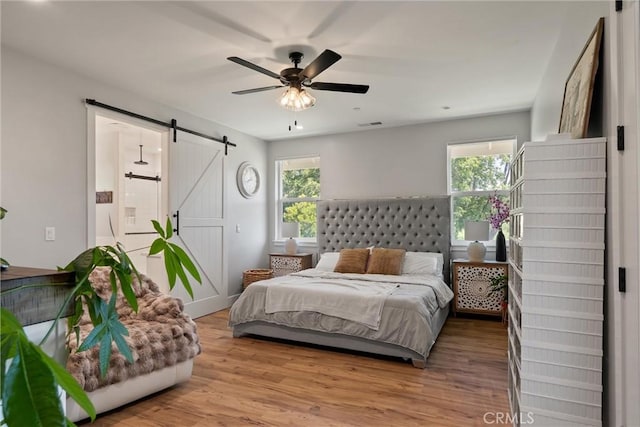 212 Valley View Dr, Paradise, CA 95969 - bedroom featuring a barn door, multiple windows, wood finished floors, and connected bathroom