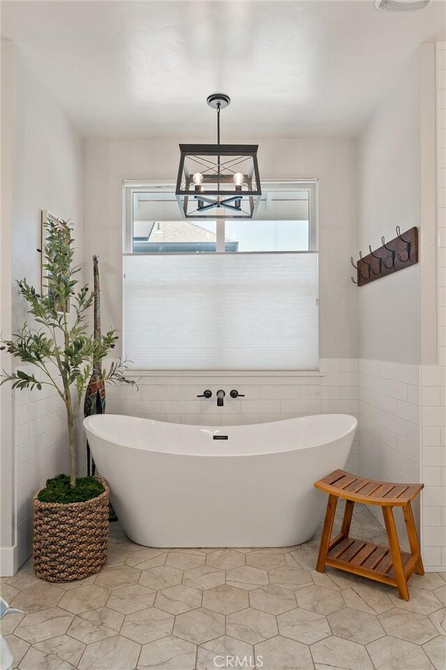 212 Valley View Dr, Paradise, CA 95969 - bathroom with tile walls, a freestanding tub, plenty of natural light, a chandelier, and wainscoting