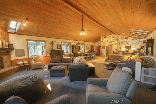 32383 Pine Manor Ln Unit 634, Running Springs, CA 92382 - carpeted living room with vaulted ceiling, a wainscoted wall, wooden ceiling, a skylight, and a stone fireplace